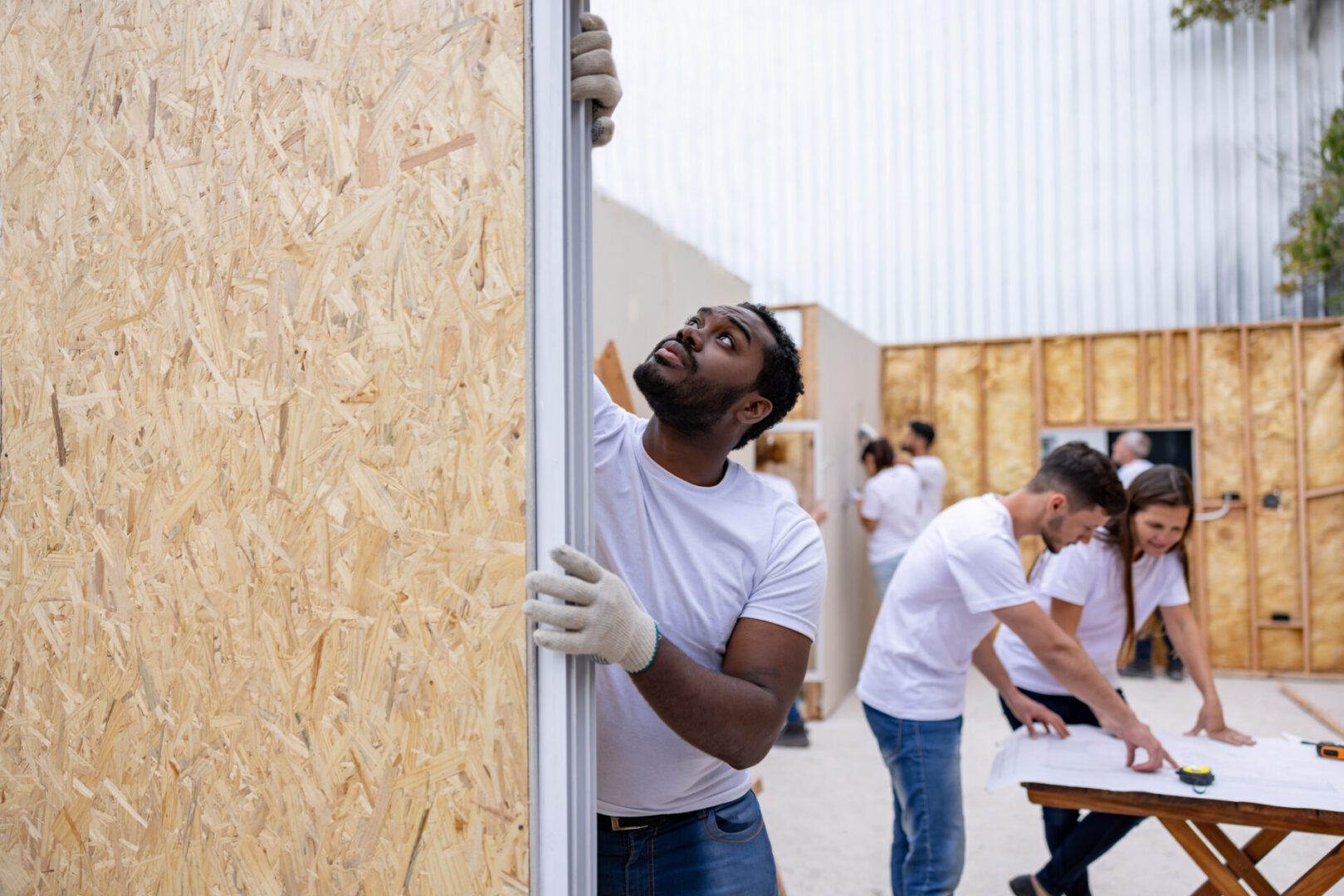 Workers assembling plywood wall at construction site
